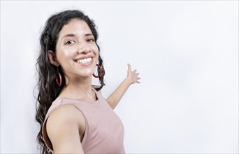 Happy Girl pointing back presenting a product. Young woman welcoming you isolated. Latin girl pointing a promotion with her palm