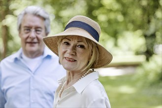 Summery dressed older woman together with her grey-haired man in the park