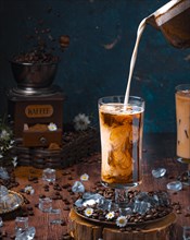 Milk is poured into glass with cold coffee