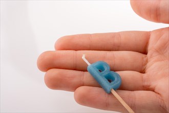 Color candle in hand on sticks writes the letter B