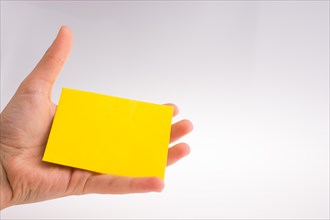 Hand holding yellow color rectangular paper on a white background