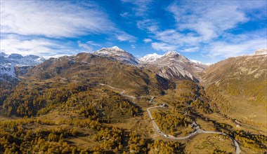 Aerial view over Val Poschiavo with its larch forests in autumn dress and the Bernina Pass road