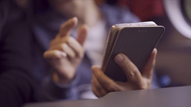 Close-up of the hands of a elderly lady sitting in a train carriageriage and using a smartphone