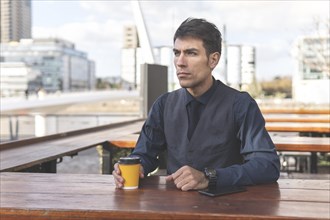 Businessman sitting at an outdoor bar having a coffee