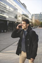Portrait of businessman walking on the street talking on the phone