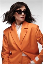 Spectacular beautiful woman in a trendy orange suit with classic make-up. Beauty face. Photo taken in the studio on a white background