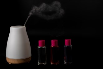 Aroma humidifier steaming with scent pots isolated on a black background