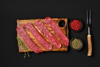 Top view of raw beef strips on black background