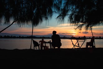Silhouette of a man enjoying the sunset view by the riverside in Kampot