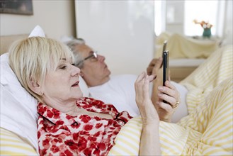 Elderly couple lying in bed together in their bedroom