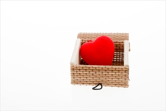 Red heart shaped object placed in a straw box on white background