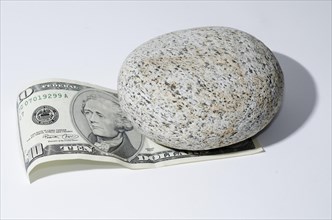 The Bill of Ten Dollar Lying Under a Stone with White Background