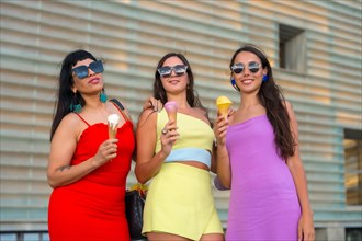 Portrait of young female friends eating ice cream on summer vacation by the beach
