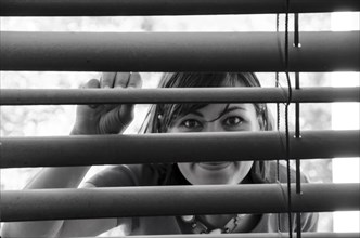 Woman Watching Out Through Window Blinds