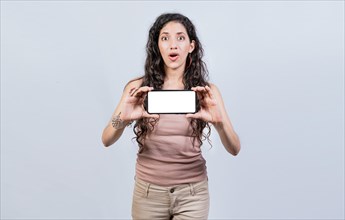 Surprised girl showing blank screen of smart phone. Latin girl showing horizontal screen of cell phone