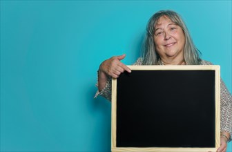 Older white-haired woman holding a blackboard with space for copying text