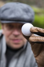 Elegant Golfer with Cap Holding a Golf Ball in Switzerland