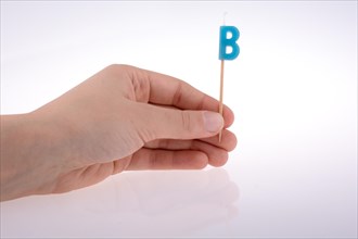 Color candle in hand on sticks writes the letter B