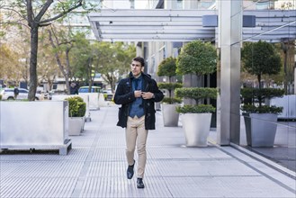 A businessman taking off the mobile phone from his pocket while walking in the street