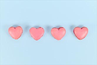 Heart shaped French macaron sweets in a row on blue background