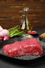 Closeup view of uncooked beef steak boneless on cast iron skillet