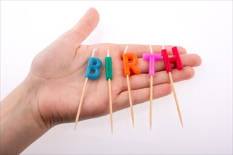 Color candles in hand on sticks write the word birth
