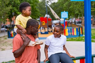 African black ethnicity father talking with his children in the playground of the city park