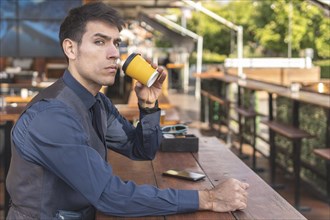Businessman sitting at an outdoor bar having a coffee