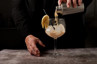 Waitress dressed in black serving a banana cocktail with ice and a slice of banana with a cocktail shaker