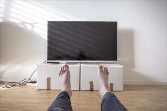 Television on Cardboard Box in Living Room and Men Legs in Switzerland