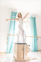 Woman Exercising on Pilates Machine Against a Window With Sunlight in Switzerland
