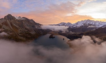 Aerial view over the fog and Lake Sils in front of sunrise in autumn