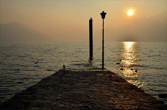 Sunset over a Foggy Alpine Lake and Pier with Mountain in Ascona