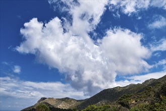 Great dynamic clouds in beautiful blue sky over hills and slope at daytime. Typical Greek landscape in spring. Sunny day hiking
