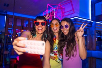 Friends at a nightclub taking a selfie at a night party on summer vacation in a pub