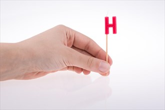 Color candle in hand on sticks writes the letter H