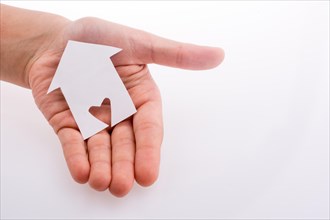 Hand holding a paper house with a heart carved in it on a white background