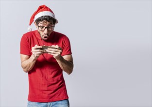 Surprised people watching a christmas promotion on the phone. Amazed man looking at a christmas offer online