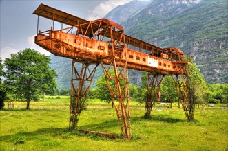 Rusty Gantry Crane on the Green Field with Mountain in Switzerland