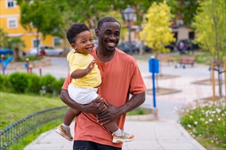 African black ethnicity father having fun with his son in playground