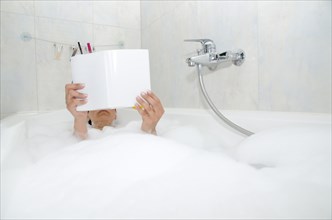 Woman reading a book in a bathtub with foam
