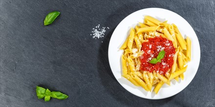 Penne Rigatoni Rigate Italian pasta in tomato sauce eat lunch dish on plate slate panorama text free space copyspace from above in Stuttgart