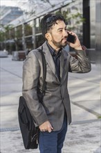 Portrait of a businessman talking on the cell phone outside his office