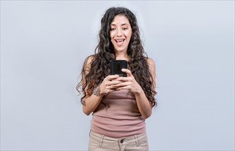 Happy and surprised girl looking at a promotion on the cell phone. Smiling woman texting with cell phone isolated. Happy latin girl using cell phone isolated