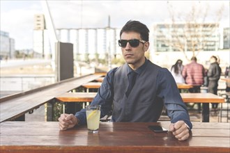 Businessman sitting at an outdoor bar drinking lemonade