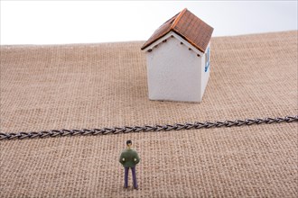 Standing man figurine and a Model house beyond the chain line on a canvas