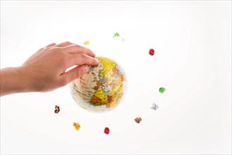 Colorful crumpled papers form a round shape around a globe under a hand