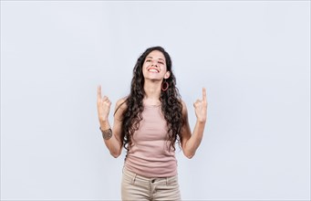 Young girl pointing an advertisement with fingers up. Smiling woman pointing with both fingers up isolated. People recommending with fingers up