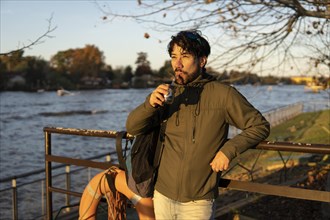 Latin man enjoying the sunset at the river while drinking mate