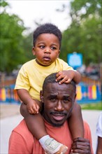 Portrait of African black ethnicity father with his children in the playground of the city park
